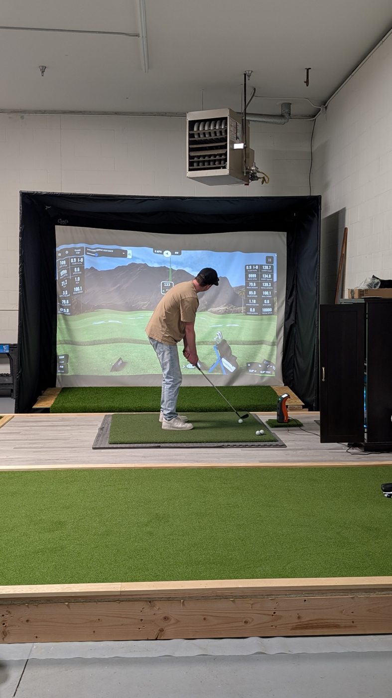 A golfer mid-swing with live launch monitor data in our demo simulator